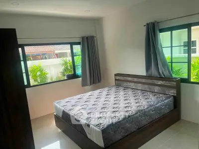Bright bedroom with large windows and modern bed frame, offering a cozy and inviting atmosphere.