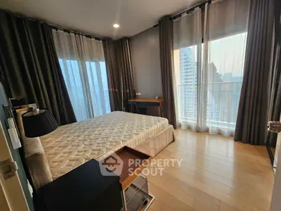 Spacious bedroom with large windows and modern decor in high-rise apartment.