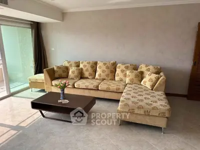 Spacious living room with elegant sofa and coffee table, featuring a large window for natural light.