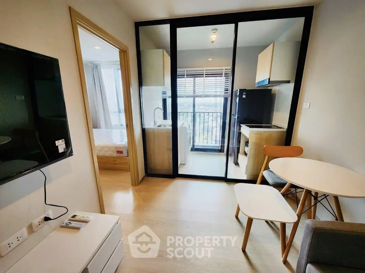 Modern apartment interior with open kitchen and cozy living area, featuring sleek furniture and natural light.