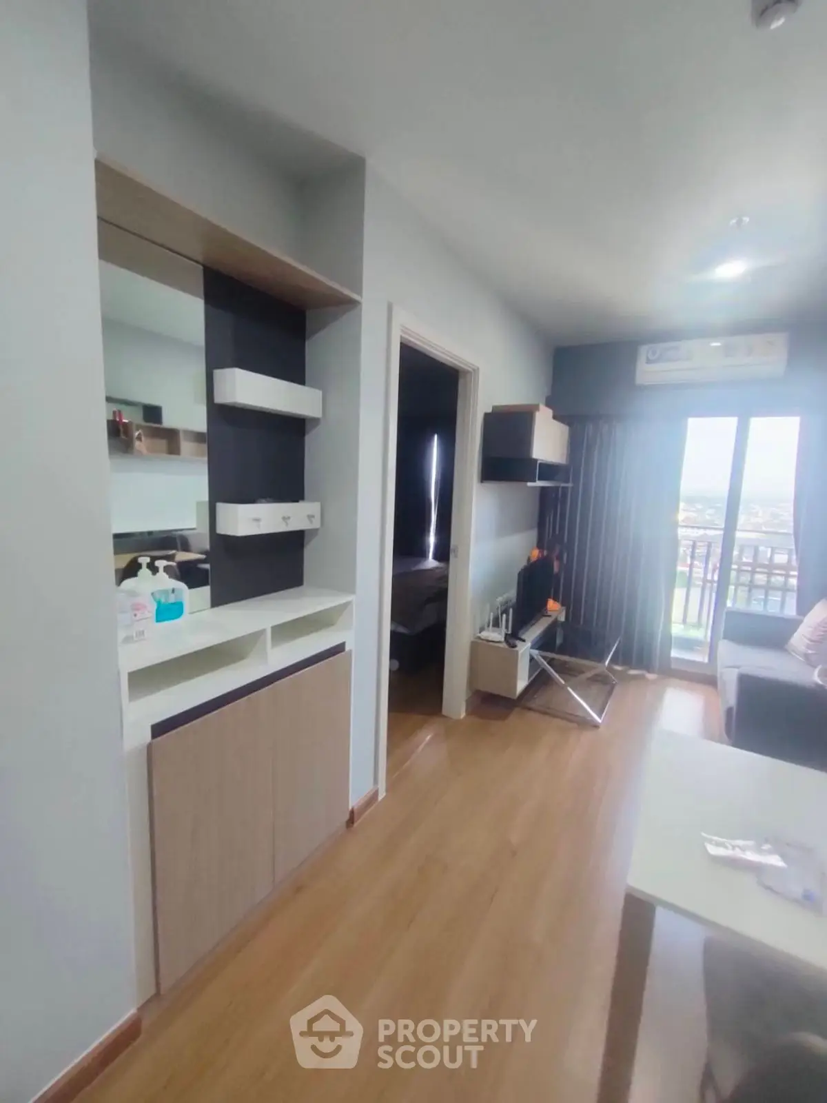 Modern apartment interior with stylish decor and wooden flooring, featuring a cozy living area and balcony view.