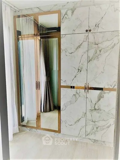 Luxurious marble wardrobe with mirrored doors in a modern bedroom setting.