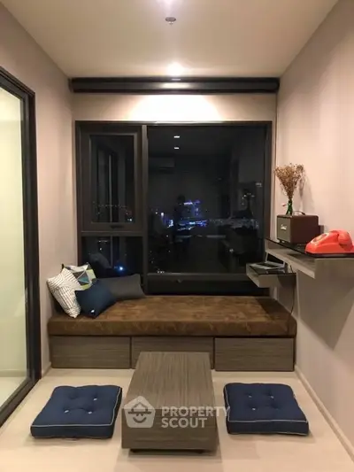 Cozy modern living room with city view, featuring a stylish daybed and chic decor.