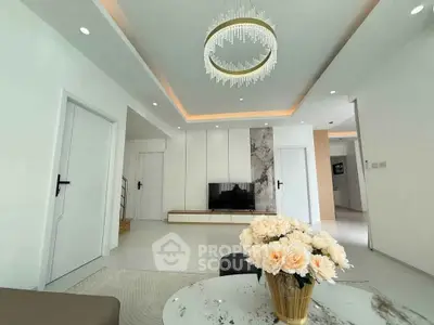 Elegant modern living room with chandelier and floral centerpiece, showcasing minimalist design.