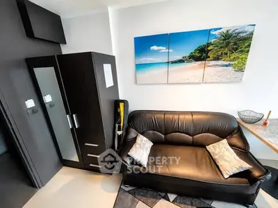 Modern living room with black leather sofa and beach artwork, featuring sleek storage solutions.