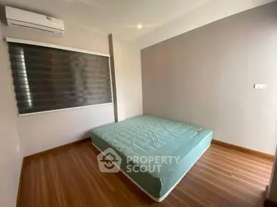 Minimalist bedroom with wooden flooring and air conditioning in modern apartment.