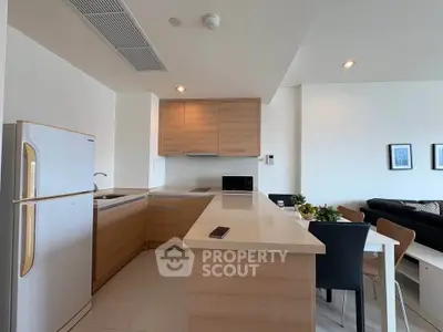 Modern open-layout kitchen with sleek wooden cabinetry and dining area in a stylish apartment.