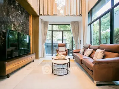 Luxurious living room with high ceilings, elegant decor, and large windows offering a serene garden view.