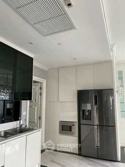 Modern kitchen with sleek appliances and minimalist design, featuring a built-in microwave and spacious fridge.