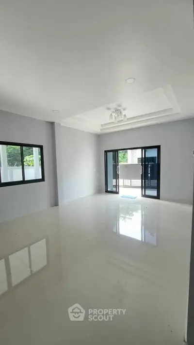 Spacious modern living room with large windows and sliding glass doors opening to a balcony.