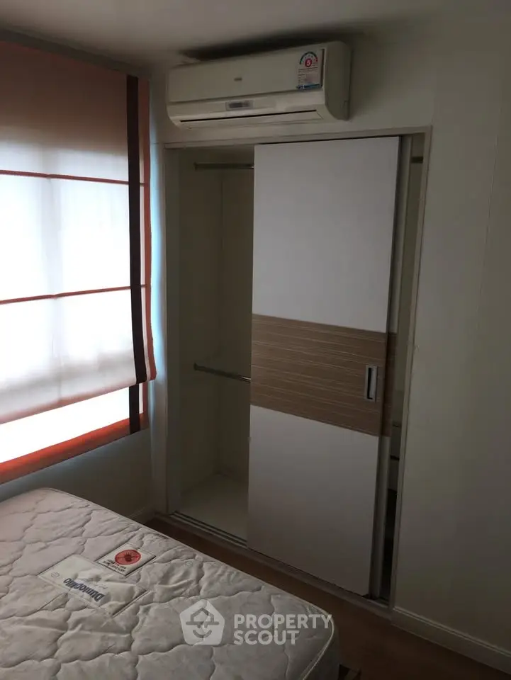 Cozy bedroom with built-in closet and air conditioning unit, perfect for comfortable living.
