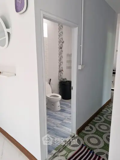 Charming hallway leading to a modern bathroom with stylish blue tiles and contemporary fixtures.