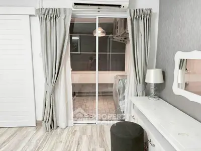 Chic bedroom with sliding glass doors leading to a cozy balcony, featuring elegant curtains and modern decor.