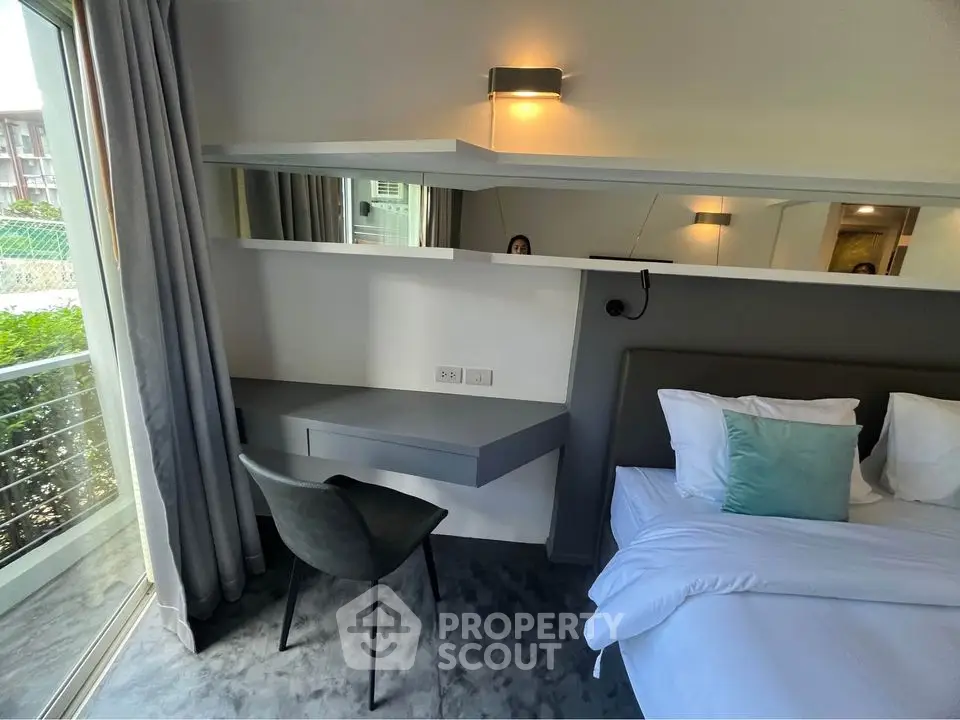 Modern bedroom with sleek design, featuring a cozy bed, stylish chair, and large window for natural light.