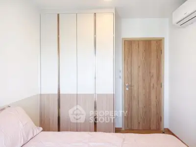 Modern bedroom with sleek wardrobe and air conditioning unit, showcasing minimalist design and comfort.