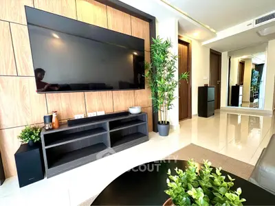 Modern living room with large TV, stylish decor, and natural light