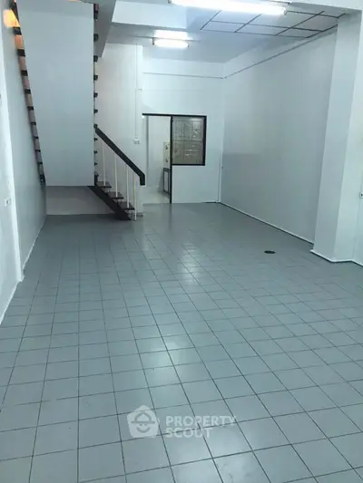 Spacious open-plan interior with tiled flooring and staircase, ideal for versatile use.