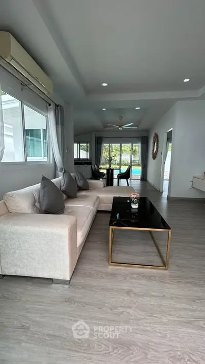 Spacious living room with modern decor and pool view, perfect for relaxation and entertainment.