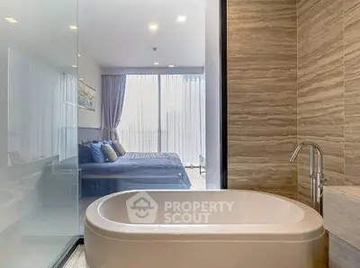 Luxurious modern bathroom with elegant bathtub and view into stylish bedroom.