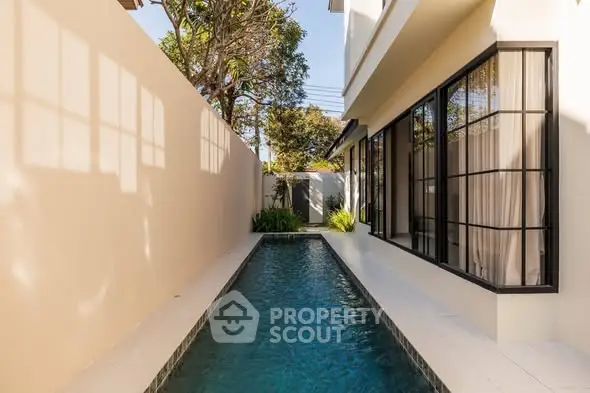 Modern narrow swimming pool alongside a stylish contemporary home exterior.