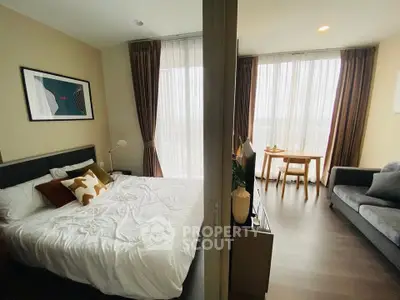 Modern bedroom with stylish decor and cozy living area, featuring large windows and elegant furnishings.