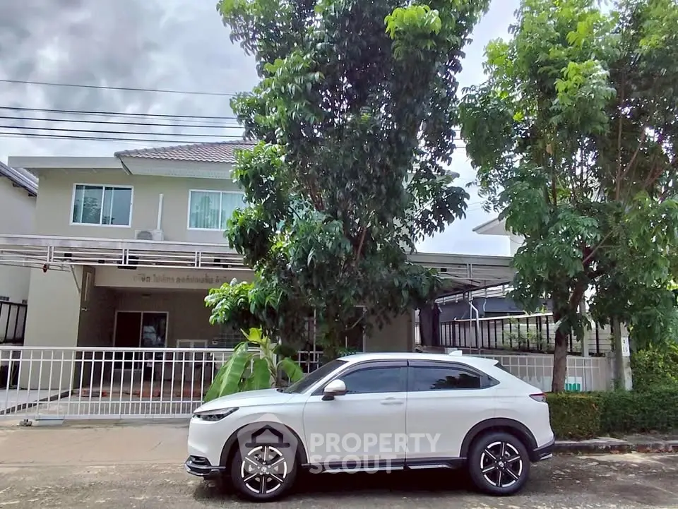 Charming suburban home with lush greenery and modern car parked in front, perfect for family living.