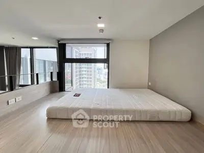 Modern minimalist bedroom with large window and city view, featuring a low-profile bed.