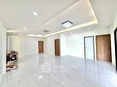 Spacious modern living room with glossy marble flooring and elegant ceiling lights.