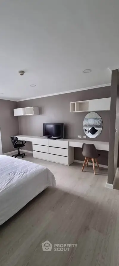 Modern bedroom with sleek furniture and workspace, ideal for comfort and productivity.