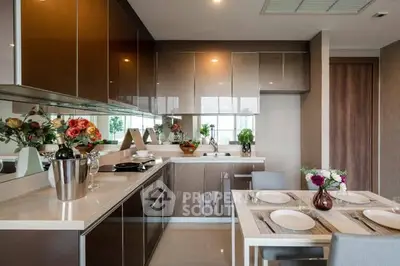Modern kitchen with sleek cabinetry and dining area, featuring elegant decor and ample natural light.