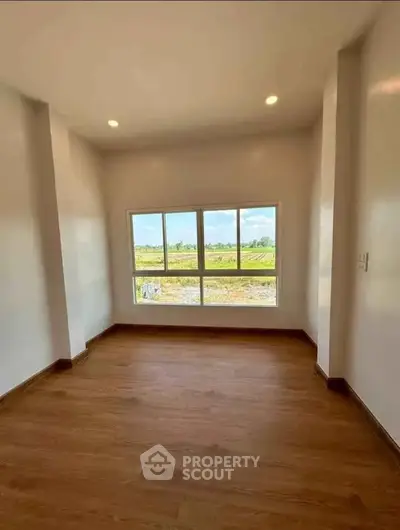 Bright room with large window offering scenic countryside view, perfect for a cozy living space.