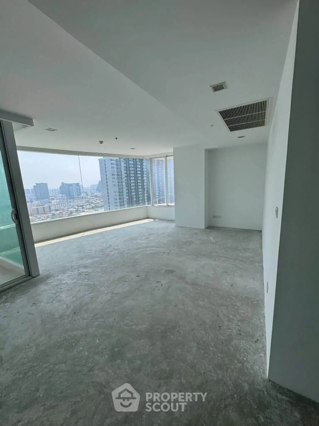Spacious empty room with large windows offering city views in modern high-rise building.