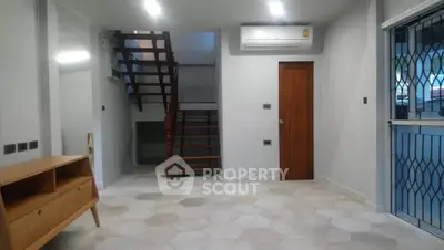 Modern living room with staircase and air conditioning, featuring hexagonal floor tiles and wooden accents.