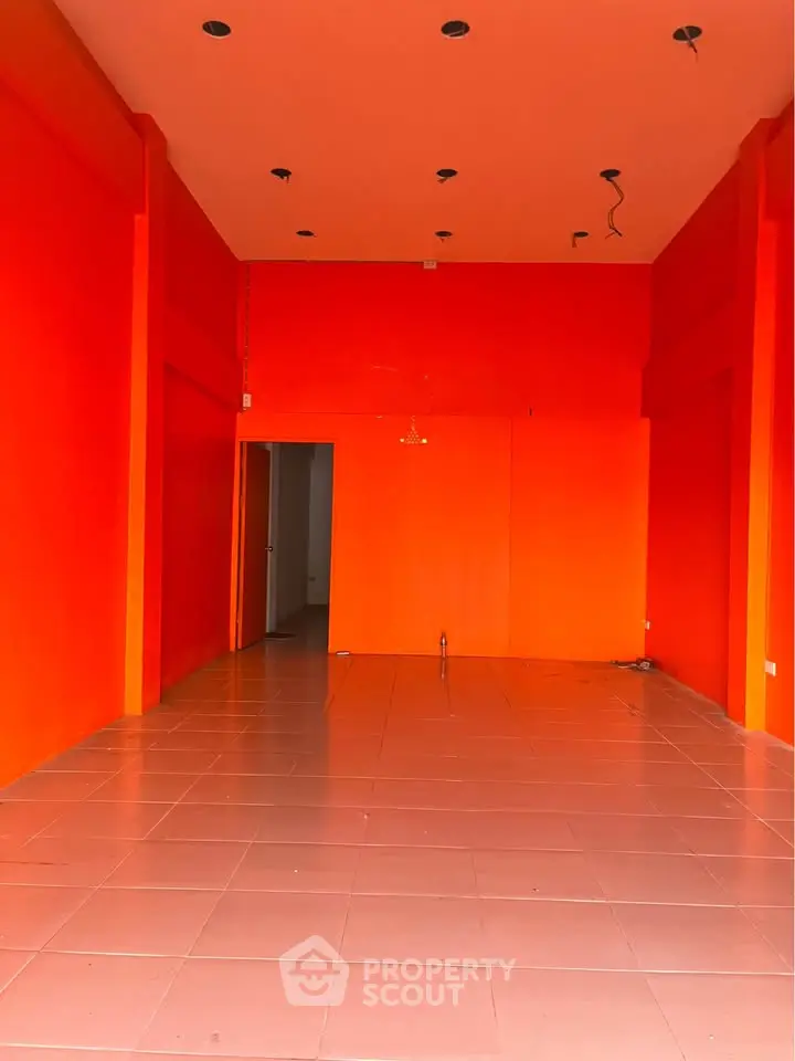Spacious commercial space with vibrant orange walls and tiled flooring, ideal for retail or office setup.