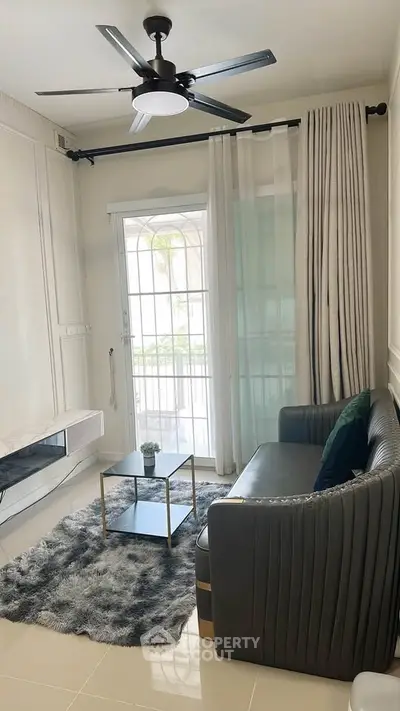 Chic modern living room with sleek sofa, stylish rug, and ceiling fan, perfect for cozy relaxation.