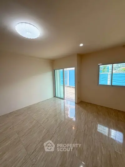 Spacious empty room with marble flooring and large windows for natural light.