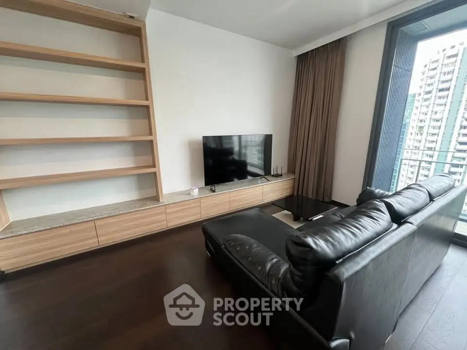 Modern living room with sleek leather sofa and built-in shelving, offering a cozy urban view.
