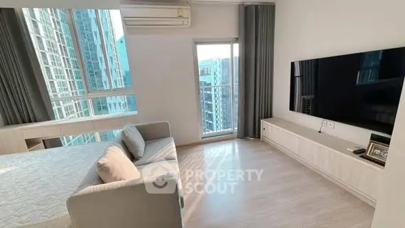 Modern living room with large TV and balcony view in high-rise apartment.
