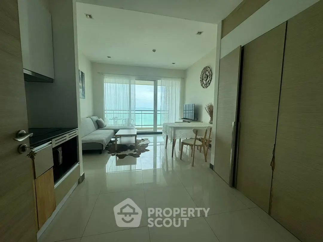Modern living room with ocean view, sleek furniture, and open layout in a high-rise apartment.