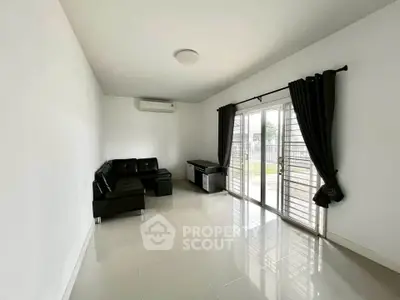 Spacious living room with sleek black sofa and large windows for natural light