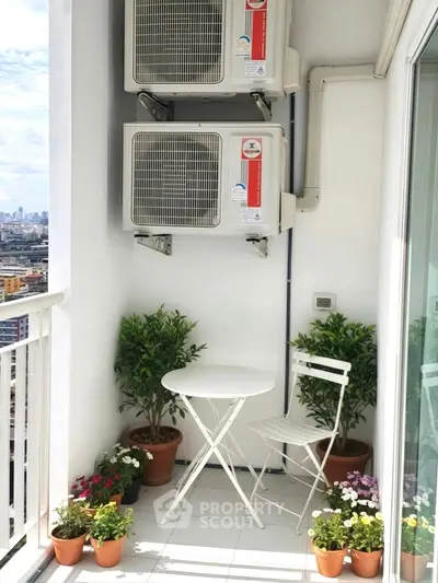 Charming small balcony with city view, featuring a cozy table and chair set, surrounded by potted plants.
