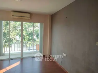 Spacious room with large windows and balcony access, featuring air conditioning and hardwood floors.
