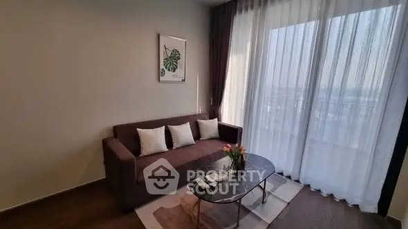 Stylish living room with modern sofa and elegant decor, featuring large windows for natural light.