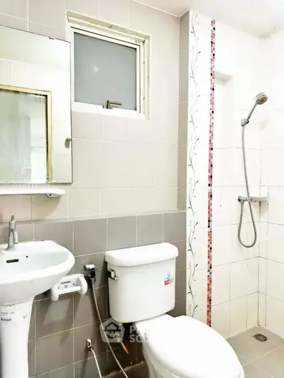 Modern bathroom with shower and sleek fixtures in a bright, tiled setting.