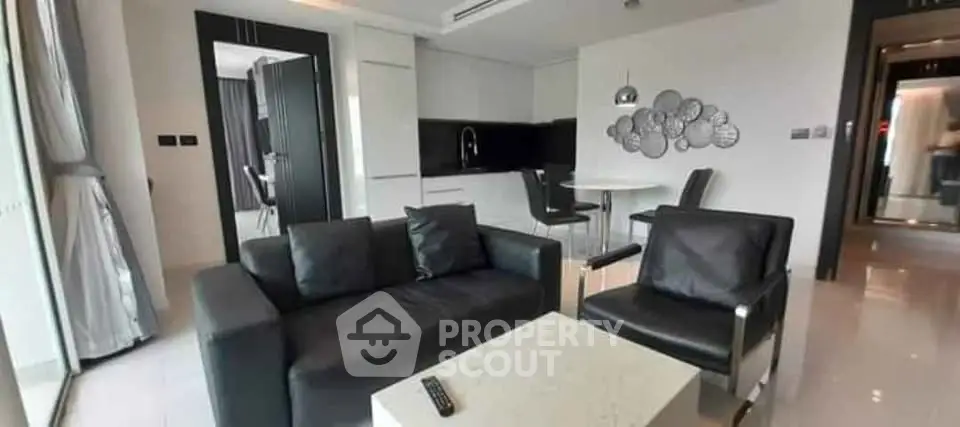 Modern living room with sleek black furniture and open kitchen layout