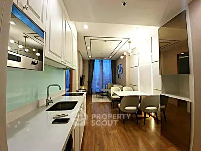 Modern open-layout kitchen and living room with elegant decor and wooden flooring.