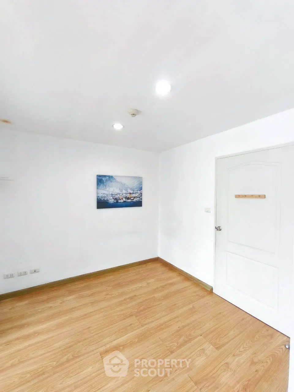 Spacious empty room with wooden flooring and white walls, ideal for customization.