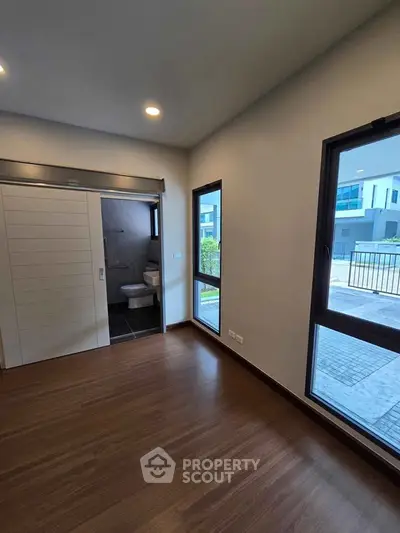 Modern bedroom with ensuite bathroom and large windows in a contemporary home
