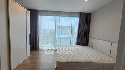 Modern bedroom with large window and minimalist design, featuring a comfortable bed and sleek wardrobe.