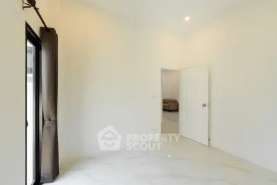 Spacious empty room with marble flooring and open door to living area